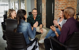 Picture of people talking with each other around a table at work.